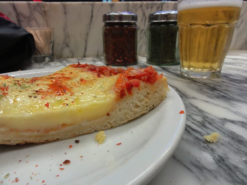 What to eat in Buenos Aires 2 Thick Argentinian pizza with pepper, oregano and a beer behind.